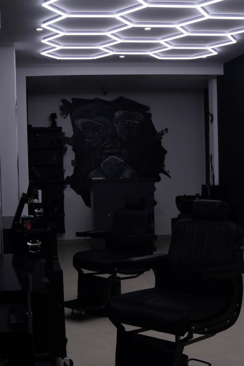 Fauteuil de barbier en cuir noir sous le plafond lumineux en nid d’abeille